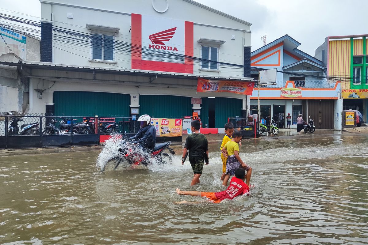 Banjir di persimpangan Jalan Taman Duta dan Jalan Raya Duta Pelni, Sukmajaya, Depok, disambut gembira sejumlah bocah, Jumat (1/12/2023) sore.