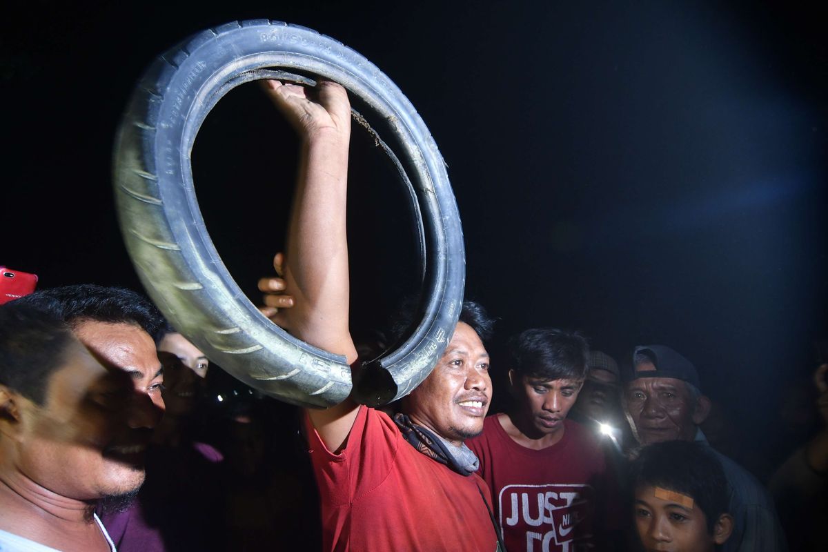 Tili (tengah), menunjukkan ban yang berhasil dilepas dari leher buaya di Sungai Palu, Sulawesi Tengah, Senin (7/2/2022). Setelah sejumlah upaya yang dilakukan sejak 2016 belum membuahkan hasil, akhirnya buaya terjerat ban di Sungai Palu berhasil diselamatkan Tili, warga Sragen, pada 7 Februari 2022 lalu.