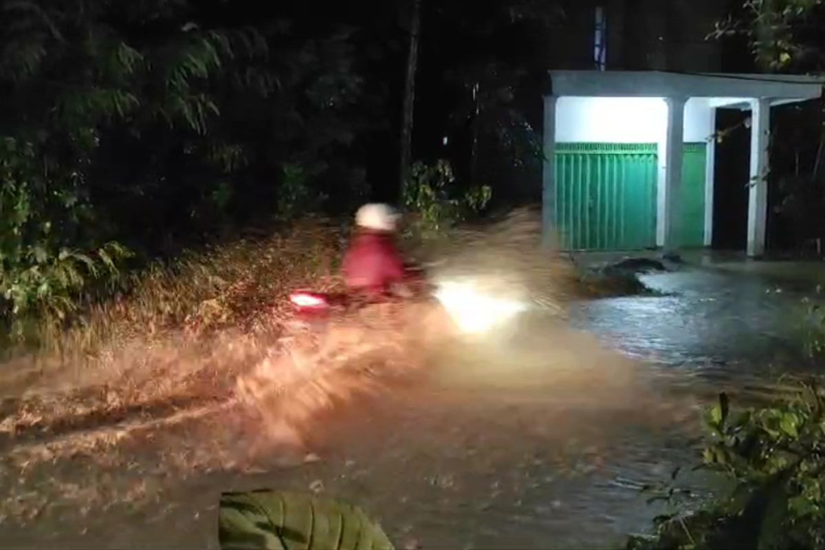 Pemotor menerobos banjir ber-arus deras, yang menggenang di Jalan Raya Ngetal Gandusari Desa Wonocoyo Kecamatan Pogalan Trenggalek Jawa Timur, Minggu (15/12/2024).