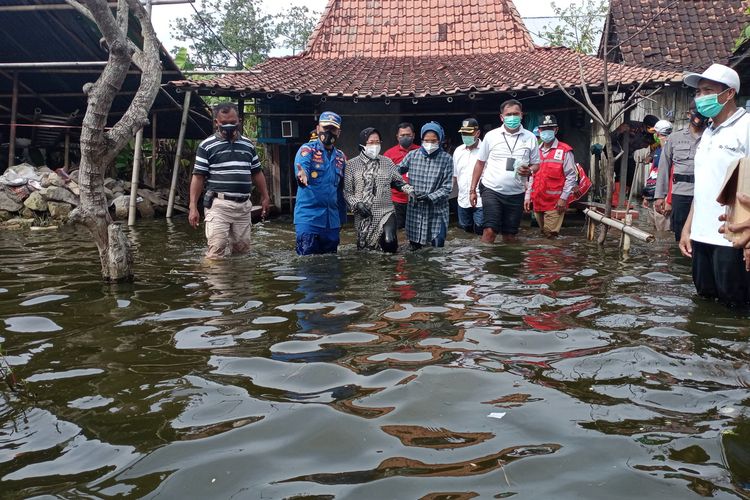 Menteri Sosial Republik Indonesia, Tri Rismaharini, menerobos genangan banjir seusai memberikan bantuan kepada korban banjir di Dukuh Dempel Desa Kalisari Kecamatan Sayung Kabupaten Demak Jawa Tengah yang sudah sepekan ini terendam banjir, Jumat (12/2/2021).