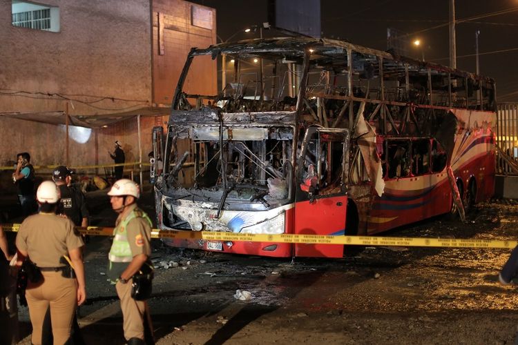 Petugas berjaga di lokasi kebakaran bus tingkat di Lima, Peru, Minggu (31/3/2019) malam.