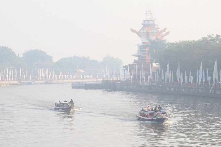 Kelotok (perahu bermesin) melintas di Sungai Martapura yang diselimuti kabut asap di Kota Banjarmasin, Kalimantan Selatan, Kamis (5/9/2019). Kota Banjarmasin terpapar kabut asap yang berasal dari kebakaran hutan dan lahan di sejumlah daerah di Provinsi Kalsel. ANTARA FOTO/Bayu Pratama S/foc.