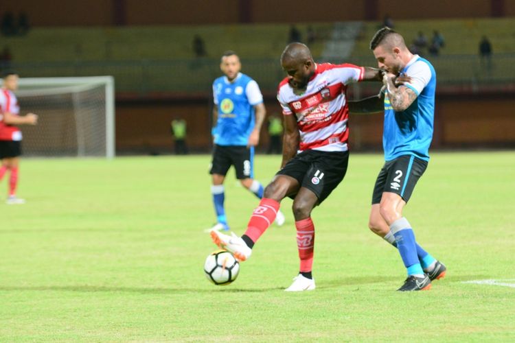 Striker Madura United, Greg Nwokolo, mencoba melewati hadangan bek Barito Putera dalam pertandingan uji coba.