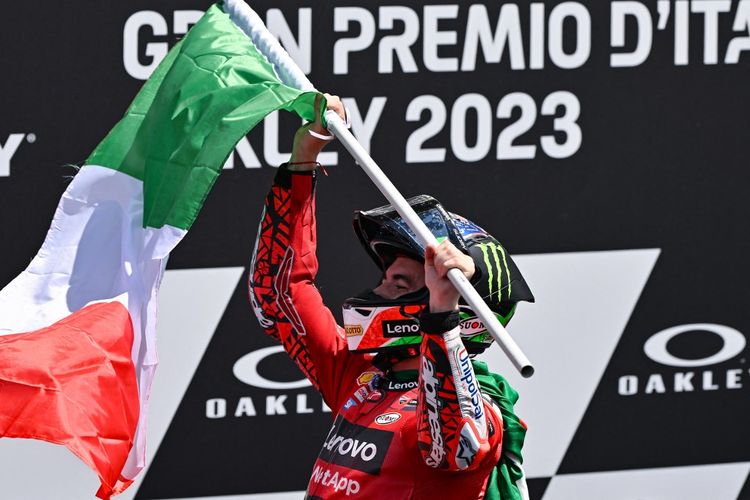 Pebalap Ducati, Francesco Bagnaia, mengibarkan bendera Italia setelah ia memenangi MotoGP Italia di Sirkuit Mugello pada Minggu (11/6/2023).