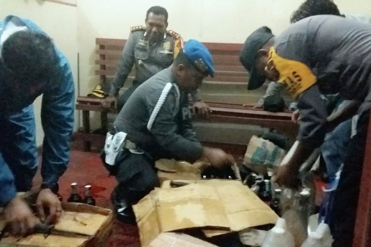 Polisi saat memeriksa barang bawaan penumpang kapal dan menemukan minuman keras (miras) jenis anggur merah yang dikemas dalam kardus di Pelabuhan Agats, Papua, Sabtu (22/9/2018).