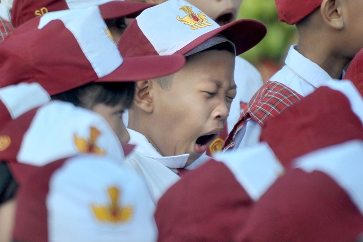 Salah satu siswa menguap di sela upacara bendera pada hari pertama masuk sekolah di Sekolah Dasar Negeri (SDN) 243 Palembang, Sumatera Selatan, Senin (16/7). Hari pertama masuk sekolah tahun ajaran 2018-2019 dimulai secara serentak di Indonesia pada Senin 16 Juli. 