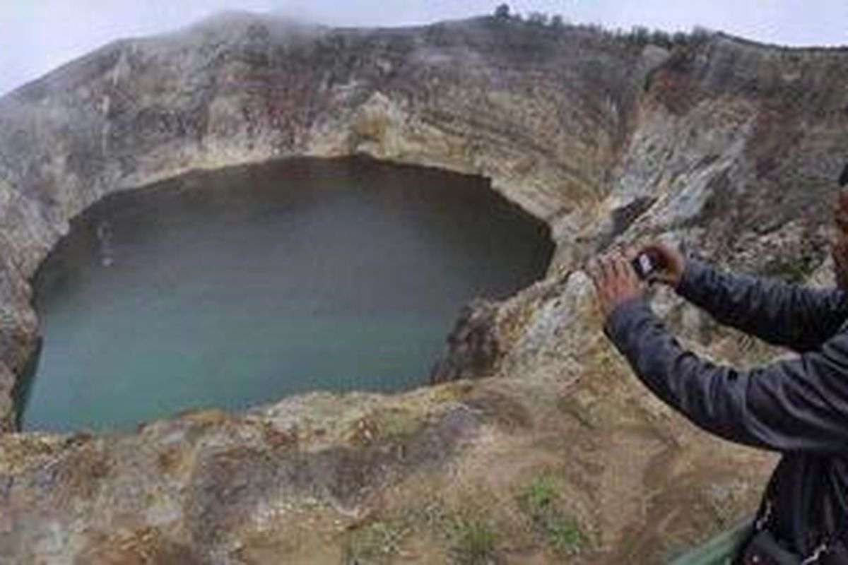 Seorang sukarelawan jagawana mengabadikan perubahan warna salah satu dari tiga danau kawah Gunung Kelimutu di Kabupaten Ende, Pulau Flores, Nusa Tenggara Timur, Selasa (19/10). Danau kawah yang biasanya berwarna hitam separuhnya mulai berubah warna menjadi hijau. Fenomena perubahan yang jarang terjadi ini terkait aktivitas vulkanik Gunung Kelimutu. 