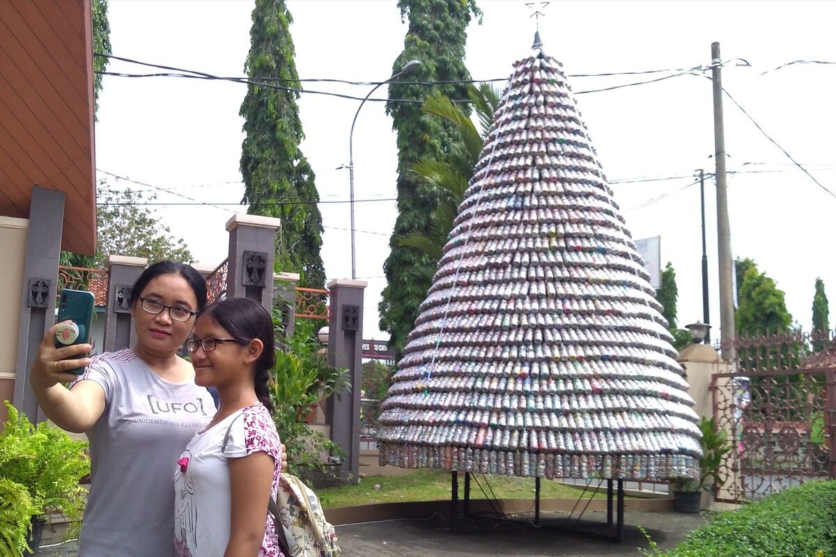 Salah satu umat berfoto dengan latar belakang pohon natal yang terbuat dari ecobrick di Gereja Katedral Krsitus Raja Purwokerto, Jawa Tengah.