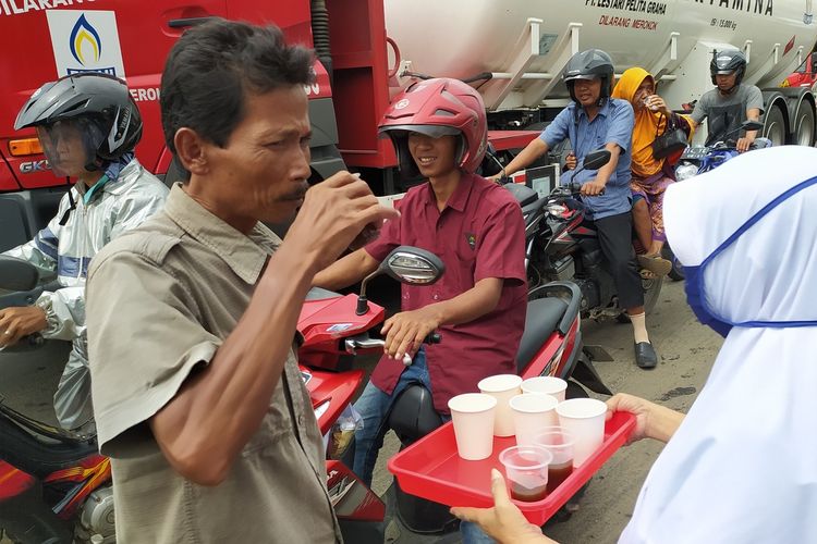 Anggota Perkumpulan Pelaku Jamu Alami Indonesia (PPJAI) membagikan jamu gratis kepada warga dan pengguna jalan di perempatan Buntu, Kabupaten Banyumas, Jawa Tengah, Kamis (5/3/3030).