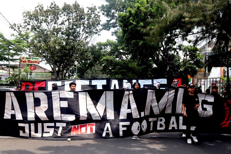 Suporter Arema, Aremania membentangkan spanduk saat melakukan aksi damai Tragedi Kanjuruhan menuntut keadilan yang dilaksanakan di 18 titik Kota Malang, Minggu (20/11/2022) siang.