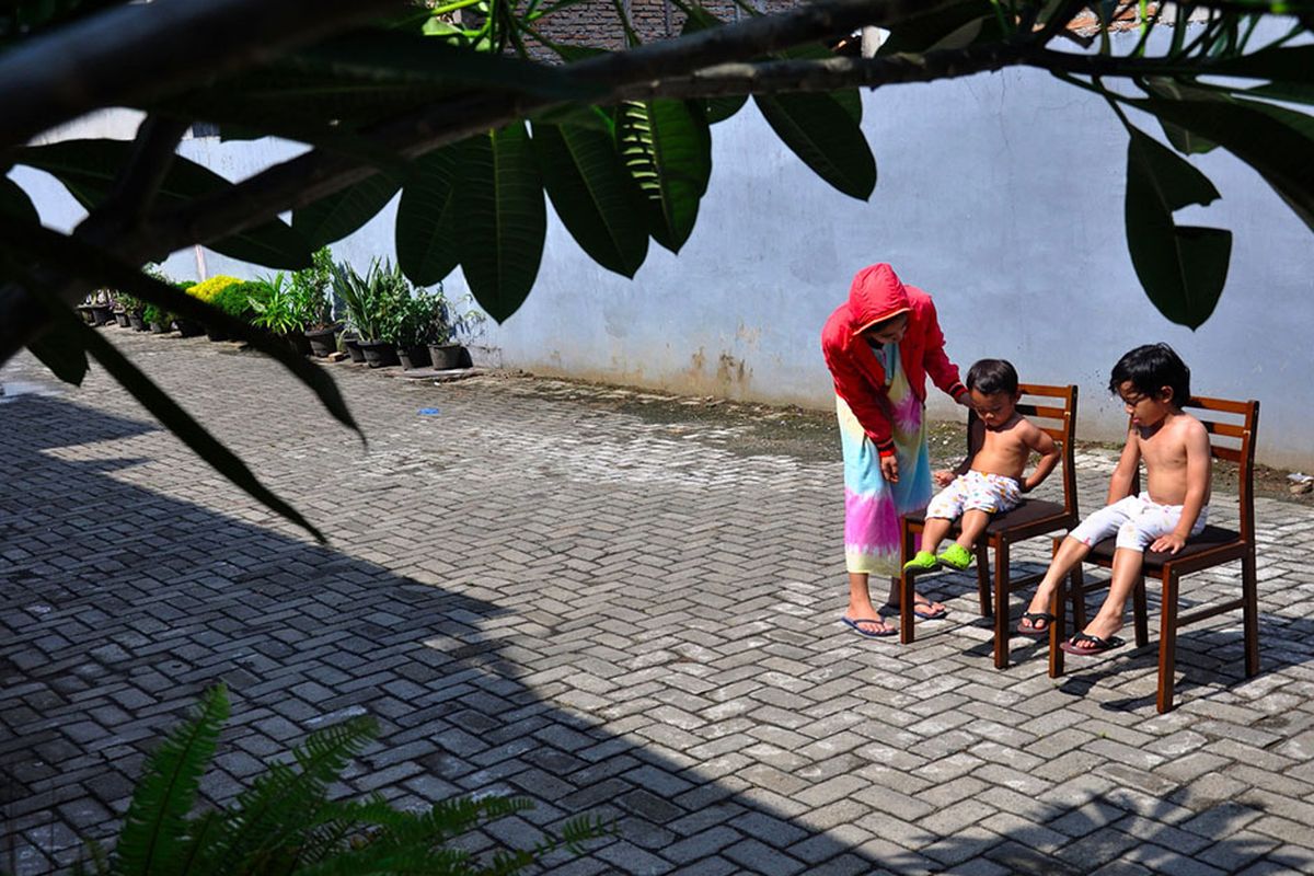 Seorang ibu menjemur kedua anaknya di bawah sinar matahari saat Self Isolation atau tinggal di rumah di Medan, Sumatera Utara, Minggu (22/3/2020). Berjemur diri di bawah matahari di antara pukul 08.00 WIB-11.00 WIB merupakan salah satu upaya yang paling sederhana untuk menjaga kesehatan selama wabah virus COVID-19.