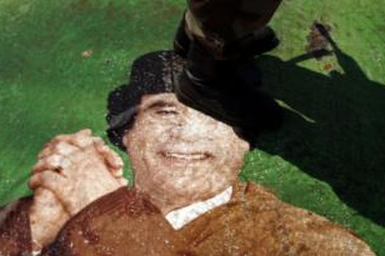 Gambar mantan Presiden Libya Moamar Khadafi diinjak oleh tentara bersenjata yang sedang berjaga di negara itu.