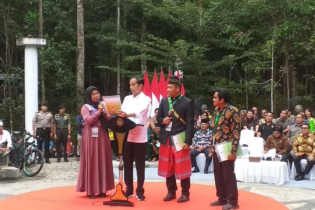 Presiden Jokowi menunjukkan SK Perhutanan Sosial kepada seorang ibu yang curhat soal lahan kebun sawitnya di eksekusi di Desa Gondai, Kabupaten Pelalawan, saat menyerahkan SK Perhutanan Sosial di Tahura Sultan Syarif Kasim, Kecamatan Minas, Kabupaten Siak, Riau, Jumat (21/2/2020).