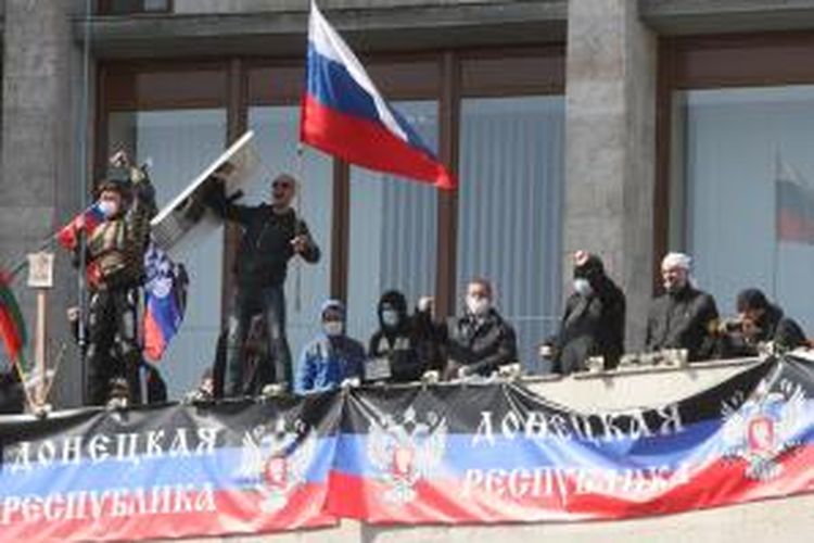 Seorang aktivis mengibarkan bendera Rusia di balkon sebuah gedung pemerintah yang mereka duduki di kota Donetsk, Ukraina setelah proklamasi kemerdekaan kota tersebut.