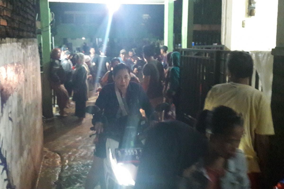 Warga RW 5 Pejaten Timur, Jakarta Selatan, meninggalkan SDN 22 Pejaten Timur yang mulai terendam banjir, Senin (5/2/2018) malam.