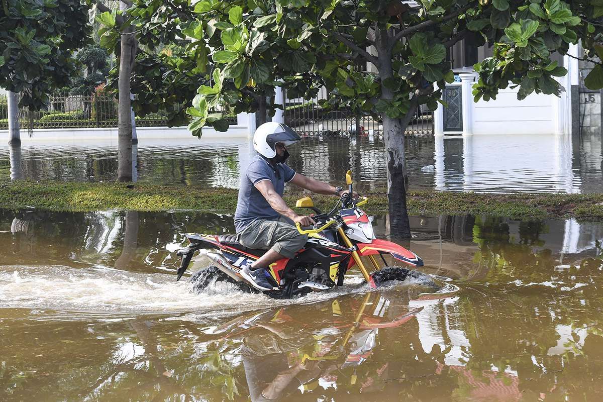 Pengendara motor melintas saat banjir rob menggenangi Kompleks Pantai Mutiara, Penjaringan, Jakarta, Minggu (7/6/2020). Banjir di kawasan tersebut diduga akibat adanya tanggul yang jebol saat naiknya permukaan air laut di pesisir utara Jakarta.