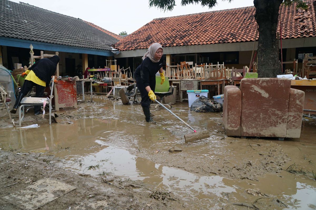 Guru dan siswa SMAN 21 Bekasi, Jatiasih, Kota Bekasi dibantu TNI AD membersihkan sisa lumpur dan genangan akibat banjir, Jumat (7/3/2025).  Banjir yang melanda kawasan Bekasi disebabkan karena meluapnya Sungai Cileungsi dan Sungai Cikeas.