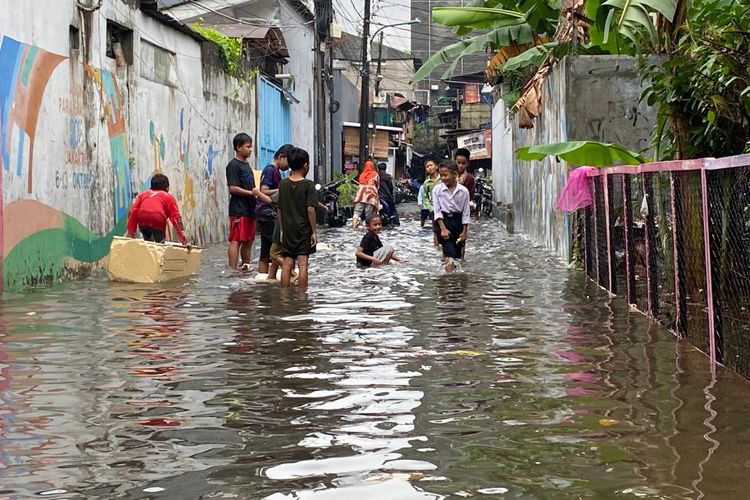 Anak-anak bermain saat banjir melanda Jalan Pembukaan 2, Grogol Petamburan, Jakarta Barat, Jumat (24/2/2023). 