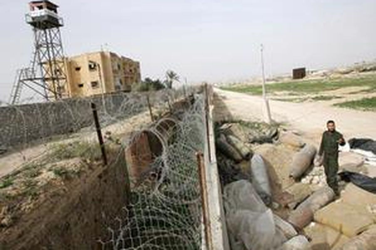 Seorang aparat keamanan Palestina berdiri dekat menara pengawas milik Mesir saat menginspeksi bom-bom Israel yang gagal meledak di Jalur Gaza, 26 Januari 2009.