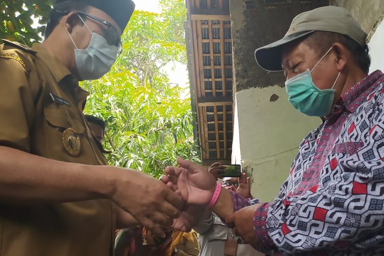 Bupati Banyumas Achmad Husein memasangkan gelang kepada warga yang komorbid di Desa Danaraja, Kecamatan/Kabupaten Banyumas, Jawa Tengah, Senin (19/10/2020).