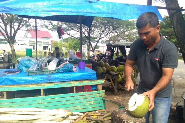 Pedagang mengupas kelapa muda di Jalan Lingkar Stadion Tunas Bangsa, Kota Lhokseumawe, Aceh, Minggu (7/1/2018).