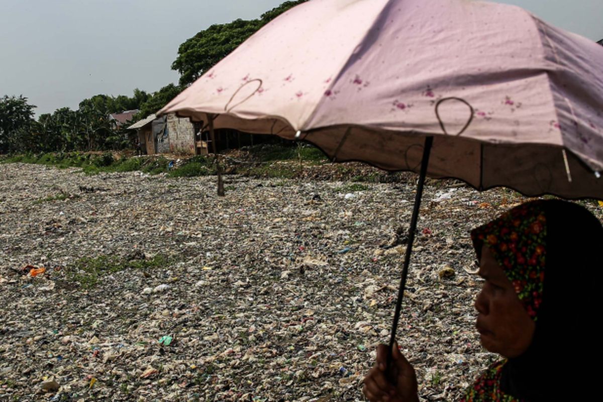 Warga melintas disamping sampah yang didominasi plastik di sepanjang Kali Pisang Batu, Desa Pahlawan Setia, Kecamatan Tarumajaya, Kabupaten Bekasi, Jawa Barat, Selasa (8/1/2019). Sampah yang memenuhi Kali Pisang Batu hingga sepanjang 1,5 kilometer berasal dari Kali Bekasi yang melewati Kota Bekasi. Sampah muncul pasca normalisasi dilakukan pada Desember 2018. Sebelumnya, kali hanya dipenuhi lumpur dan eceng gondok.