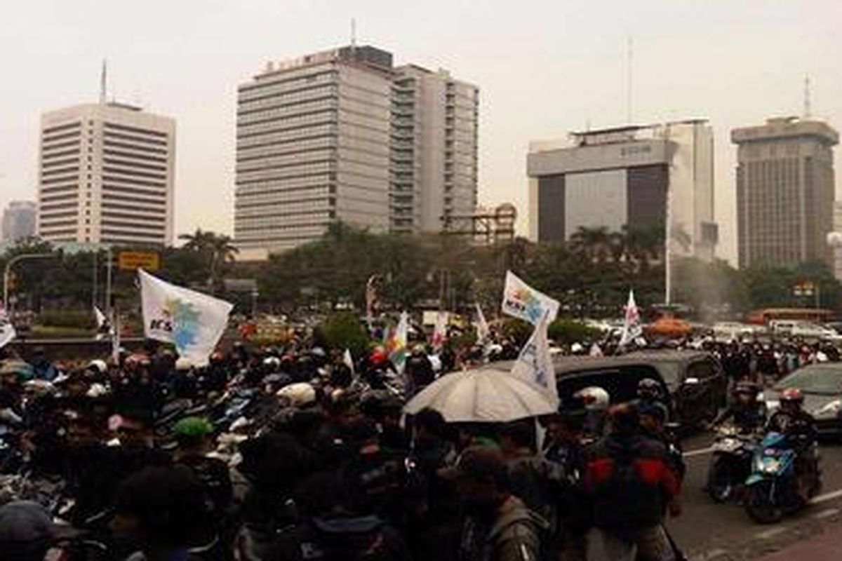 Rombongan pekerja tiba di kawasan patung Arjuna di depan Gedung Indosat, Jakarta Pusat, Kamis (12/7/2012).   