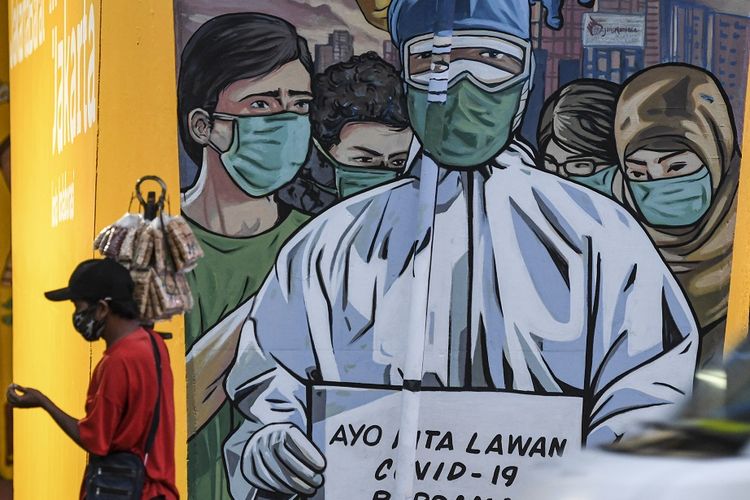 Seorang pedagang yang mengenakan masker melintas di depan mural imbauan untuk melawan COVID-19 di Jakarta, Minggu (29/11/2020). ANTARA FOTO/M Risyal Hidayat/aww.