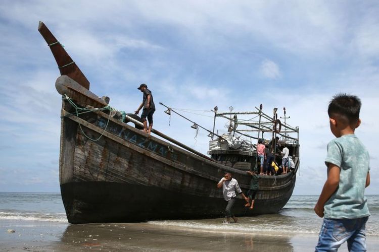 Warga melihat kapal kayu yang ditumpangi imigran Rohingya hingga terdampar di pesisir pantai Lamreh, Aceh Besar, Aceh, Minggu (10/12/2023).