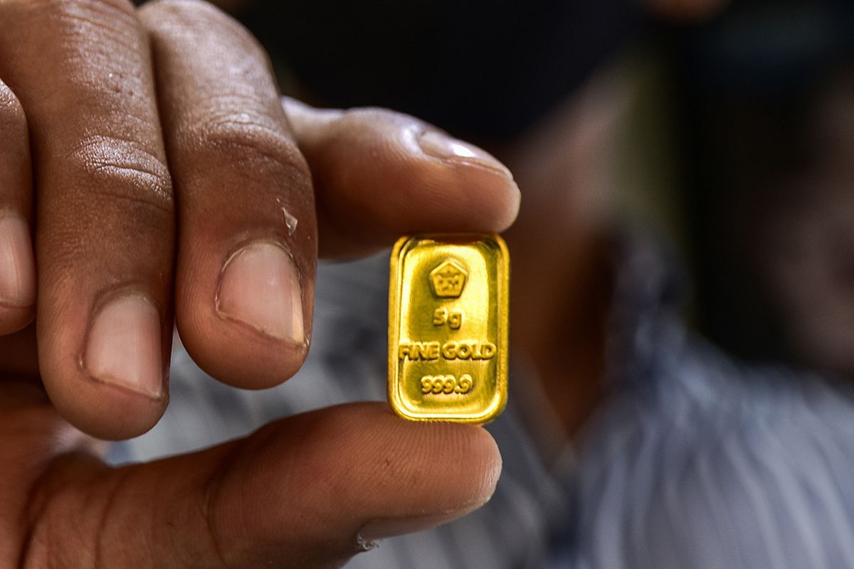 Seorang pegawai menunjukkan kepingan emas di sebuah toko perhiasan di Kota Pekanbaru, Riau, Selasa (28/7/2020).