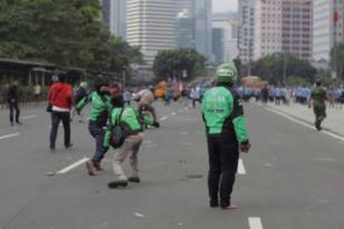 Sejumlah pengemudi ojek online terlibat aksi saling lempar batu dengan para sopir taksi yang berdemonstrasi di Jalan Sudirman, Jakarta, Selasa (22/3/2016). Aksi ini dipicu karena salah satu pengemudi ojek online disweeping oleh para demonstran.