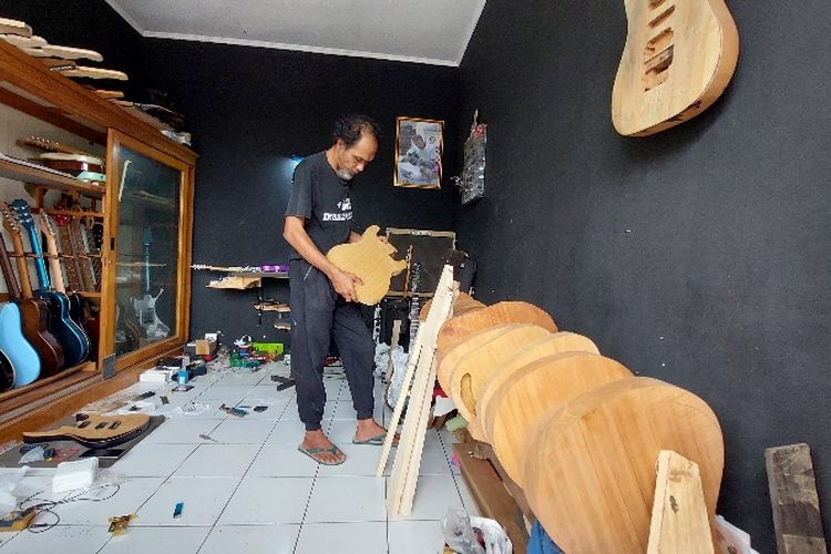Slamet Joko Santoso mengecek bodi yang akan digunakan membuat gitar pesanan pelanggan