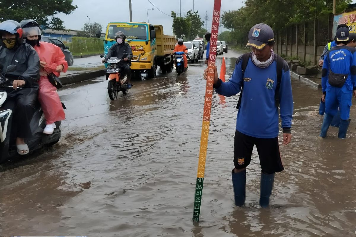 Petugas Satuan Tugas Sumber Daya Air Kecamatan Cilincing mengukur tinggi muka air yang merendam Jalan Marunda Makmur, Jakarta Utara, Senin (27/2/2023).