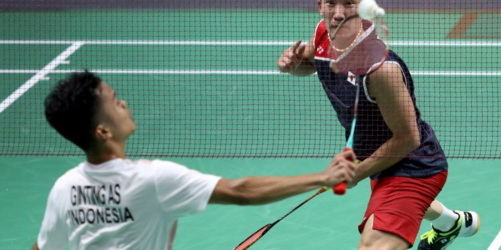 Pebulu tangkis putra Indonesia Anthony Sinisuka Ginting (kiri) berupaya mengembalikan kok ke arah lawannya pebulu tangkis putra Jepang Kento Momota (kanan), pada pertandingan babak semifinal beregu putra Asian Games 2018 di Istora Senayan, Jakarta, Selasa, (20/8/2018).  - INASGOC