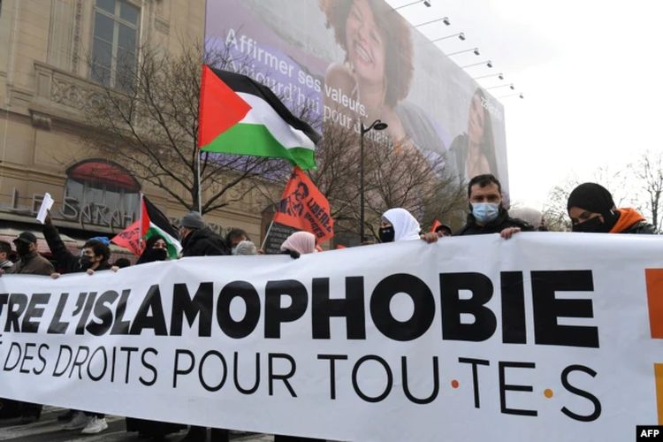 Para pengunjuk rasa membentangkan spanduk dan bendera Palestina dalam unjuk rasa menentang RUU antiseparatisme dan Islamofobia di Paris, Perancis, 21 Maret 2021.