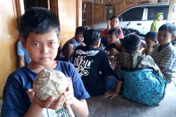 Seorang bocah menunjukkan bola batu yang ditemukan terpendam di tanah Desa Banjarejo, Kecamatan Gabus, Grobogan, Jateng, Kamis (15/6/2017).
