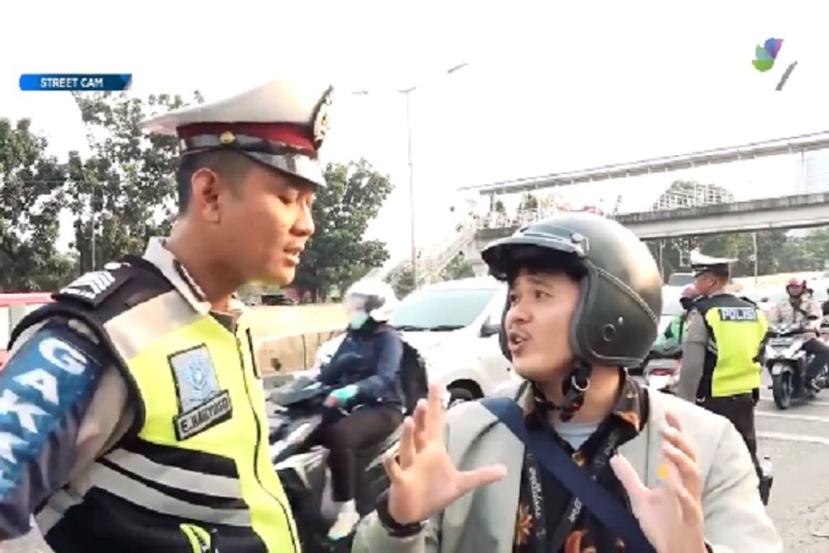 Polisi berdebat dengan pengendara motor.