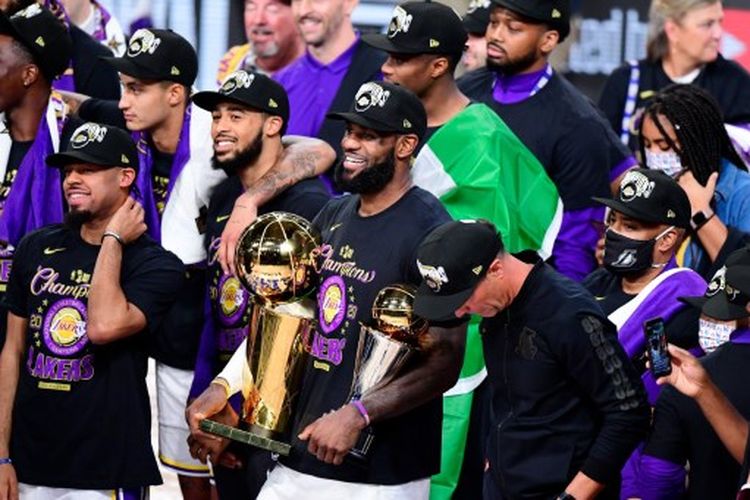 LeBron James (tengah) membawa trofi juara NBA dan pemain terbaik Final NBA seusai mengantar LA Lakers mengalahkan Miami Heat pada Gim 6 Final yang berlangsung di AdventHealth Arena, Orlando, Amerika Serikat, Senin (12/10/2020) pagi WIB.