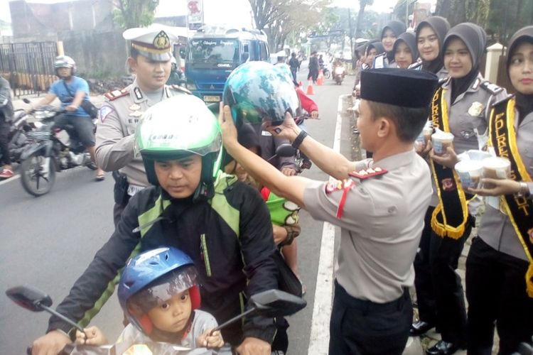 Kapolres Garut memasangkan helm kepada istri seorang pemotor yang melintas di depan Mapolres Garut, Kamis (17/5/2018).