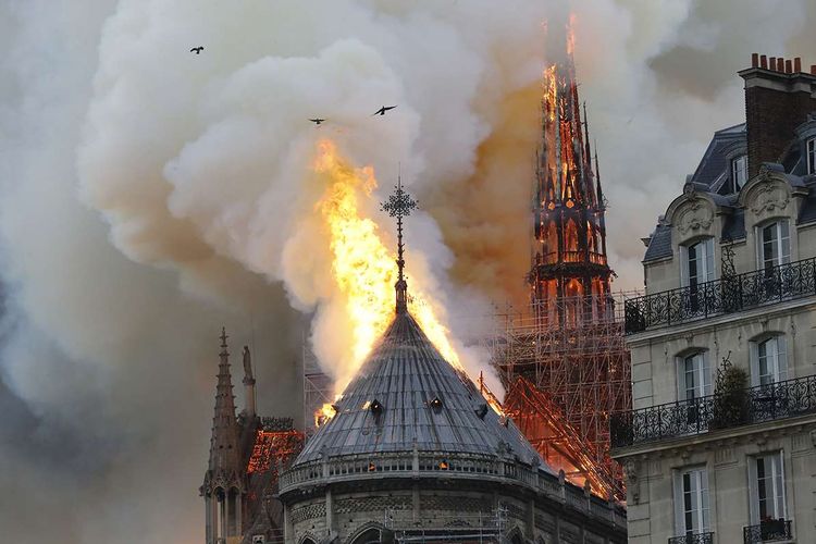 Api membakar bagian atas Gereja Notre Dame di Paris, Perancis, pada Senin (15/4/2019). Belum diketahui penyebab pasti kebakaran itu, api dengan cepat melalap atap dan puncak menara gereja bernuansa Gotik yang dibangun pada abad ke-12 itu.