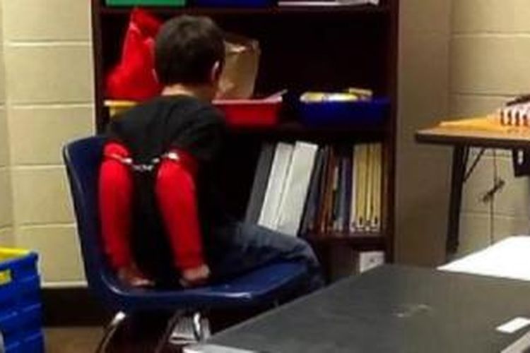 Dalam foto yang diambil dari sebuah rekaman video ini terlihat seorang bocah laki-laki penderita ADHD diborgol petugas keamanan sekolah setelah dianggap mengganggu kawan-kawan sekelasnya.