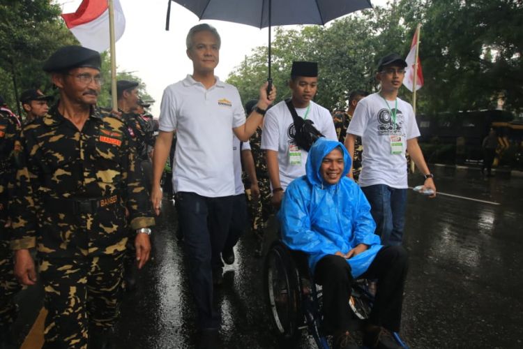 Gubernur Jawa Tengah Ganjar memayungi salah satu penyandang disabilitas pada Sabtu (23/2/2019). 