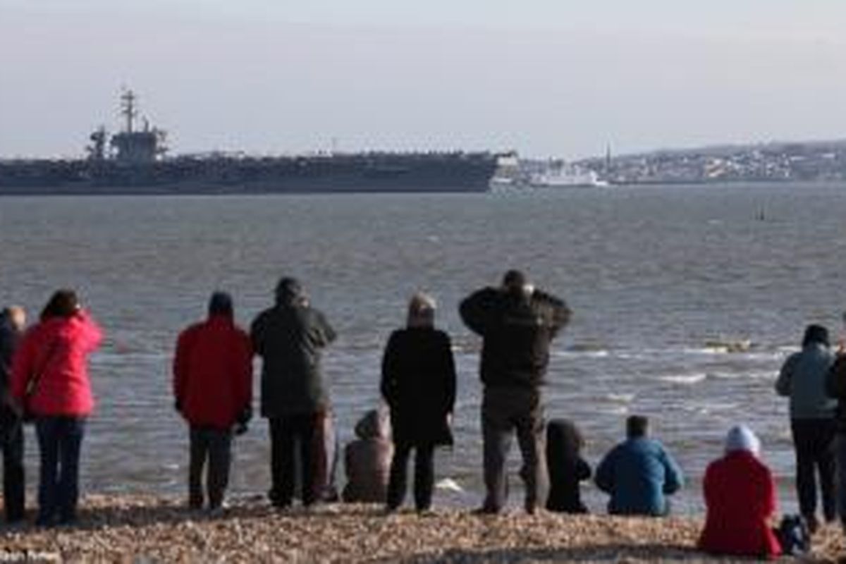 Warga Inggris menyaksikan kapal induk AS USS Theodore Roosevelt yang berbobot mati lebih dari 100.000 ton itu yang terpaksa buang sauh di Teluk Stokes setelah pelabuhan Portsmouth tak mampu menampung kapal raksasa itu.