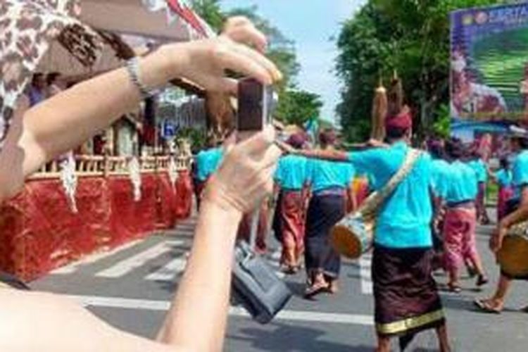 Sejumlah penari dan seniman yang akan menyemarakkan pawai budaya di pembukaan Pesta Kesenian Bali XXXVI, mengadakan latihan di depan Monumen Perjuangan Rakyat Bali Bajra Sandhi, Renon, Denpasar, Kamis (12/6/2014). Seorang wisatawan mengabadikan latihan para penari dan seniman itu. Pesta Kesenian Bali XXXVI dibuka Jumat (13/6/2014).