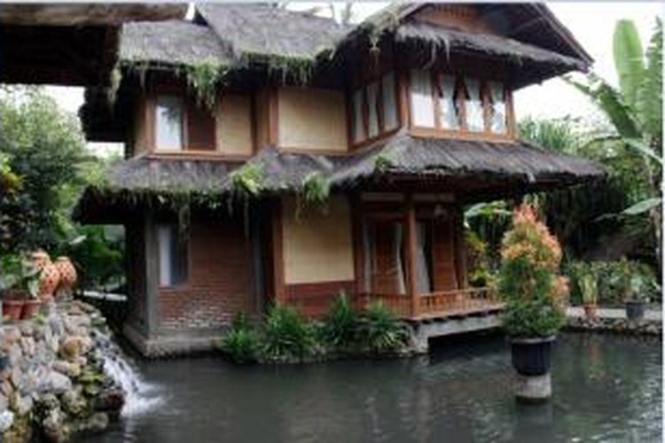 Rumah panggung itu berdiri di atas kolam. Bertingkat dua, seluruh material utamanya menggunakan bahan alami. Pondasinya tampak kokoh dibuat dari kayu kelapa. 