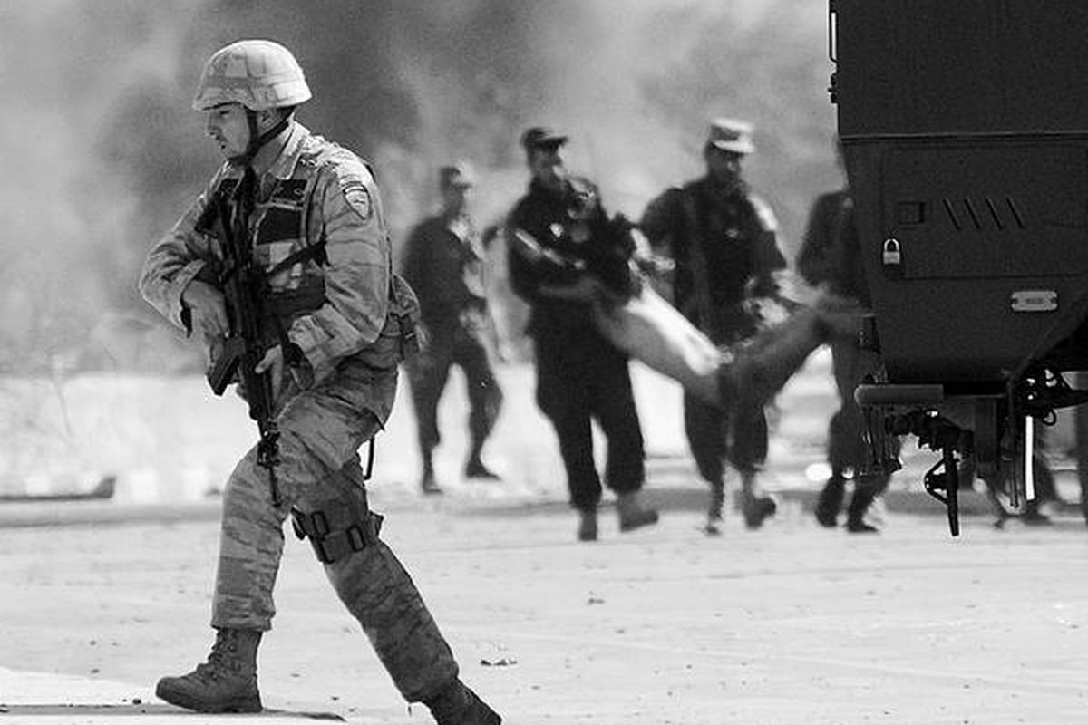 Polisi Afganistan(di latarbelakang) menolongseorang lelakiyang cedera, setelah terjadi serangan bom bunuh diri di dekat pintu gerbang masuk pangkalanNATO di Kabul,Afganistan Selasa (8/9). Dua orang tewas dan setidaknya 10 orang cedera.