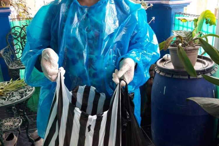 Tampak salah satu warga Cipageran Asri mengenakan jas hujan saat hendak mengirimkan pasokan makanan kepada keluarga yang tengah dalam masa karantina mandiri di kota Cimahi.