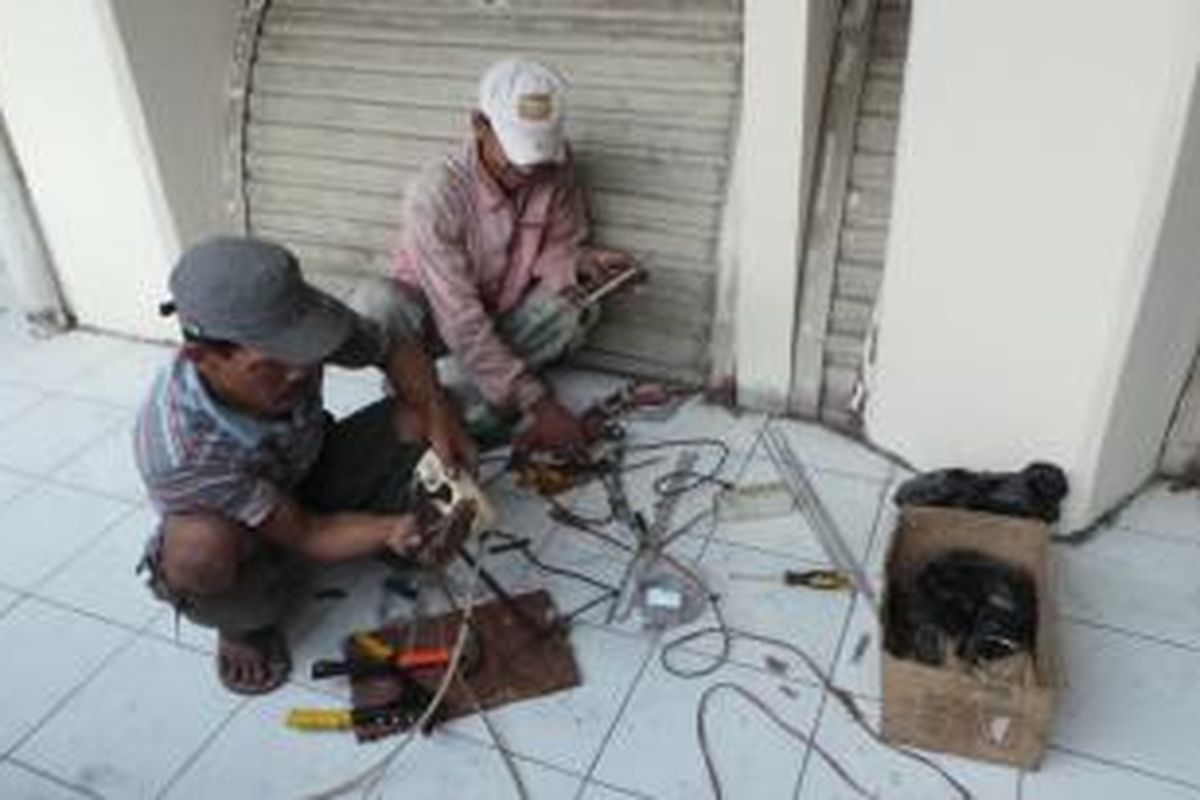 Dua pekerja tengan memperbaiki rolling door yang rusak di Blok G Pasae Tanah Abang, Jakarta Pusat, Selasa (12/8/2013).