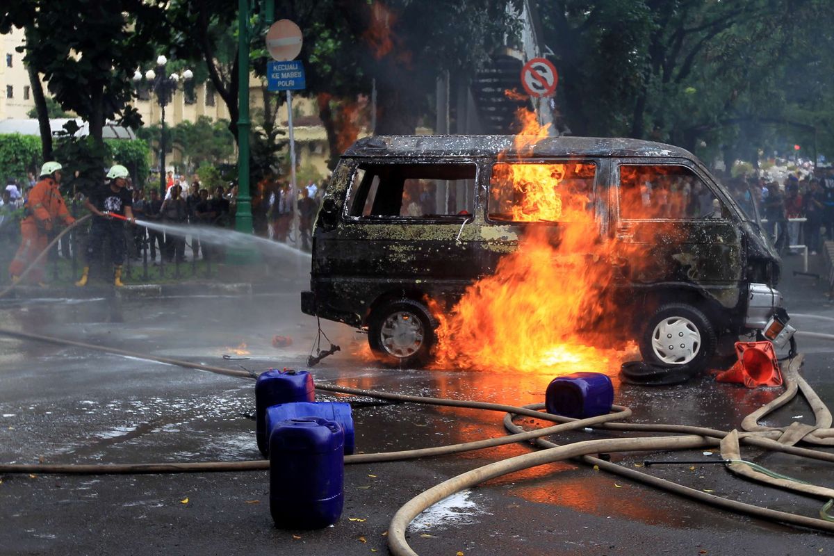 Petugas berusaha memadamkan mobil Daihatsu Zebra B2791AJ yang terbakar di Jalan Trunojoyo, samping Mabes Polri, Kebayoran Baru, Jakarta, Rabu (4/2/2015). Mobil itu membawa lima tangki berisi ratusan liter bahan bakar minyak.  KOMPAS IMAGES/KRISTIANTO PURNOMO