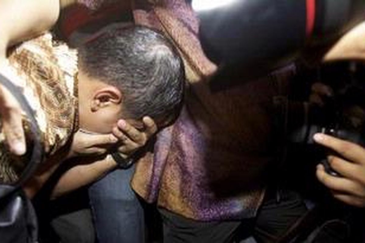 Mantan pegawai Ditjen Pajak, Dhana Widyatmika menutup wajah saat keluar dari ruang pemeriksaan Tindak Pidana Khusus, Kejaksaan Agung, Jakarta, Kamis (1/3/2012). Tersangka kasus dugaan korupsi dan pencucian uang tersebut diperiksa lebih kurang 10 jam terkait rekening gendut yang dilaporkan Pusat Pelaporan dan Analisis Transaksi Keuangan (PPATK).